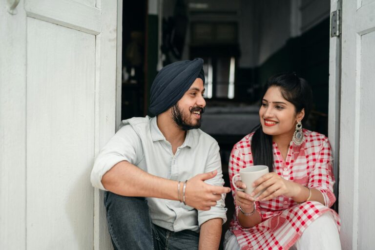 Indian couple abroad smiling while talking over coffee