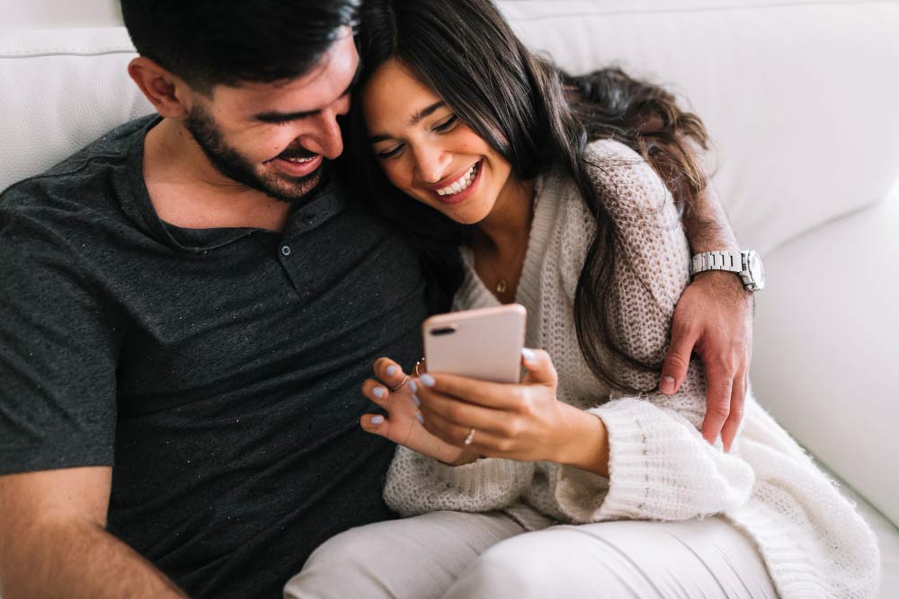 Happy Indian couple using a dating app on a smartphone, representing Indian Dating Tips in the USA for singles seeking love and relationships