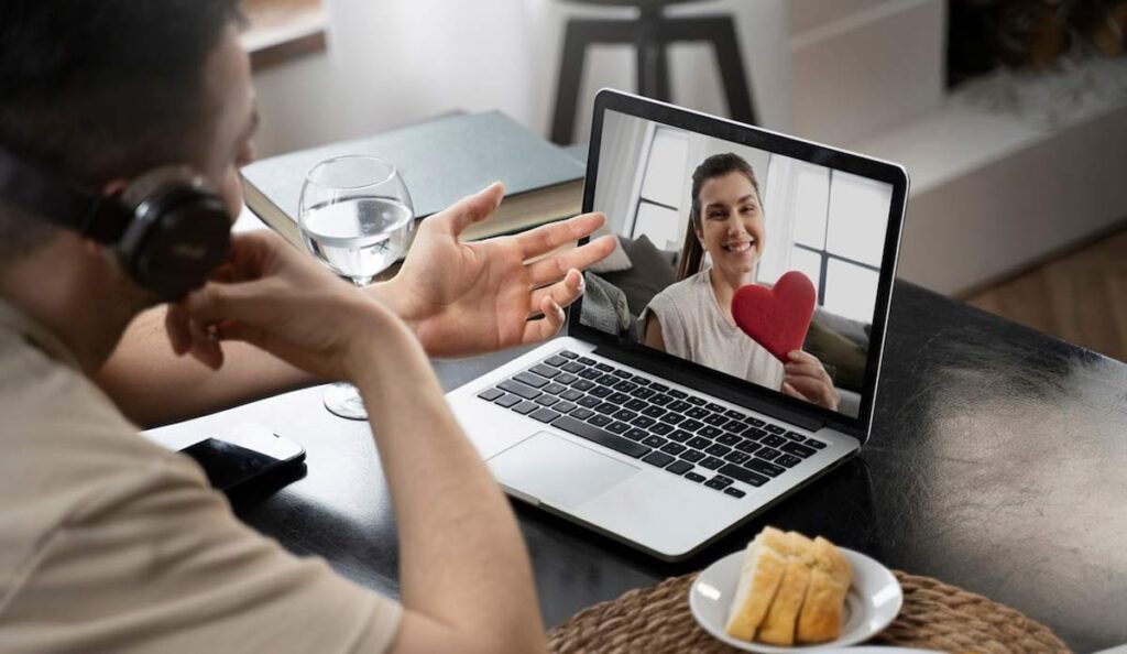 A couple smiling while video calling on laptops, with a calendar or clock in the background to symbolize planning and consistency.